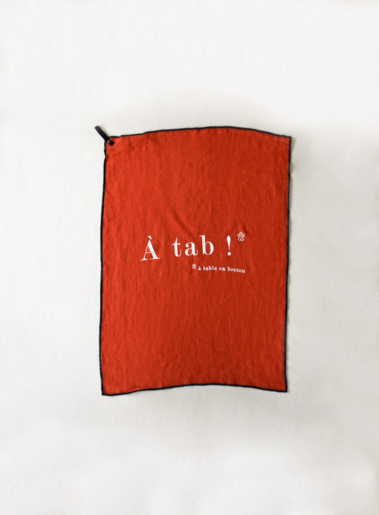 Torchon Nolan couleur rouge citrouille sérigraphie blanche "à tab" qui signifie "à table" en breton